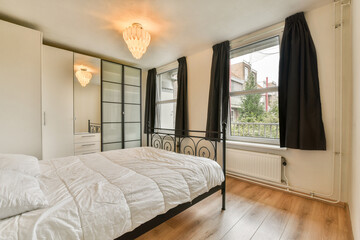 A stylish and minimalistic bedroom showcasing a sleek bed, elegant lighting, and large windows, promoting a serene and inviting atmosphere.