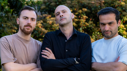 Obraz premium Close-up of three middle-aged businessmen standing in a wooded area, arms crossed, with determined gazes reflecting business focus