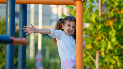 Obraz premium A cute little girl child joyfully playing in a children's park surrounded by trees on a fall day