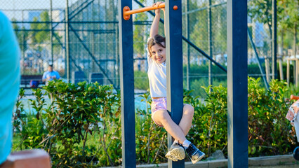 A cute little girl child joyfully playing in a children's park surrounded by trees on a fall day