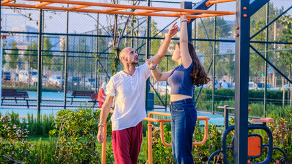 Fototapeta premium A slightly overweight teenage girl playing in the park with her father on a fall day