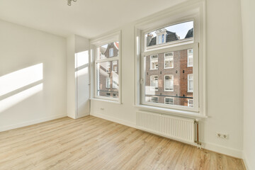 Spacious room featuring large windows allowing ample natural light, wooden flooring, and a simple design. Ideal for creating a cozy living space.
