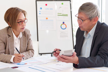 Senior executives discussing financial reports and company growth strategies while reviewing data...