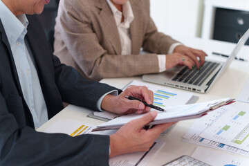 Senior business professionals analyzing financial data together, reviewing reports and discussing...