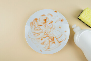 Dirty white plate bottle of dishwashing liquid sponges on beige background. Top view.