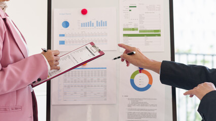 Senior professionals analyzing financial data on a whiteboard, discussing investment strategies,...