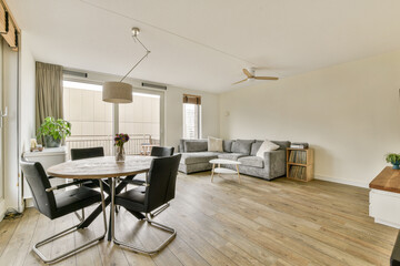 Bright and airy living room featuring contemporary furniture, a round dining table, and large...