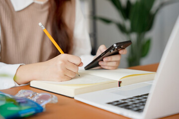 Asian girl student doing exam hand holding pencil writing answer in university classroom education high school or university student taking notes while preparing for exam