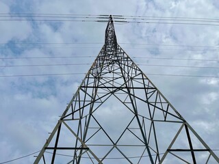 High voltage transmission tower under cloudy sky during daytime