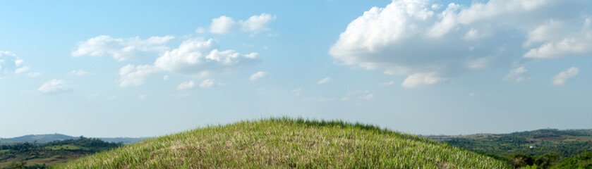 Fototapeta premium eco-Tourism Adventure Preservation Concept, Lush green hill under a clear blue sky with soft clouds, evoking tranquility and nature's beauty.
