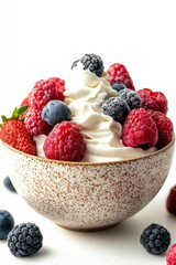 Delicious bowl filled with fresh raspberries blueberries blackberries and strawberry on whipped cream dessert close up shot against white background