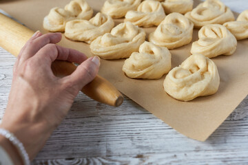 Close-up of women's hands, yeast dough for scones and a rolling pin.