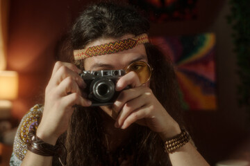 Individual focusing on taking picture with vintage camera in artistical nostalgic mood and dressed in bohemian style