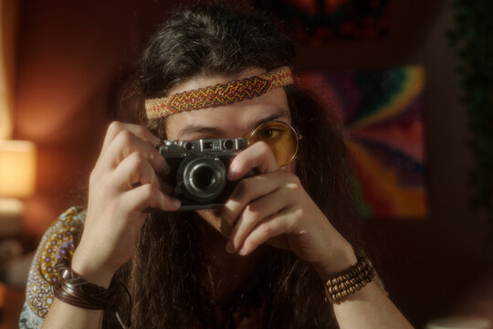 Individual focusing on taking picture with vintage camera in artistical nostalgic mood and dressed in bohemian style
