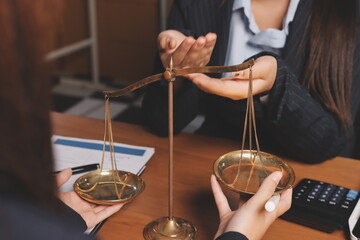 Attractive young lawyer in office Business woman and lawyers discussing contract papers with brass scale on wooden desk in office. Law, legal services, advice, Justice and real estate concept.