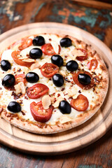 Spicy pizza with jalapeno pepper, chorizo ​​sausage, black olives and mozzarella cheese. Wooden background. Soft focus.