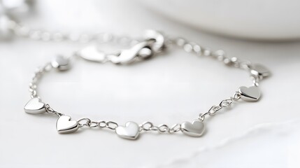 A delicate sterling silver bracelet with small heart-shaped charms, placed on a white background