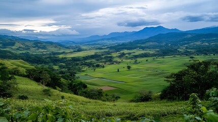 Obraz premium Lush Green Valley Amidst Mountains Under Dramatic Cloudy Sky : Generative AI