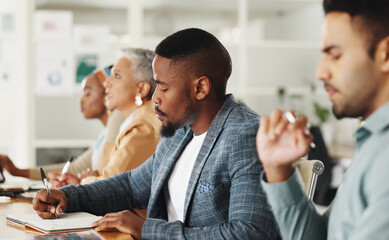 Business people, office and writing notes in group, training or watch video for development in career. Men, women and listening to tutorial with notebook, coaching or studying at creative workplace