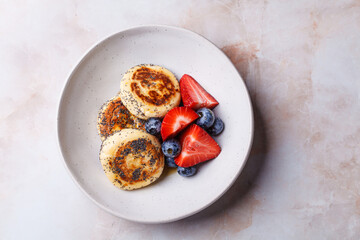 Cottage cheese pancakes with poppy seeds, syrup and berries.