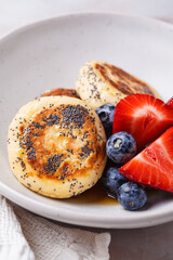 Cottage cheese pancakes with poppy seeds, syrup and berries.