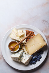 Cheese plate for party with honey, nuts and berries.