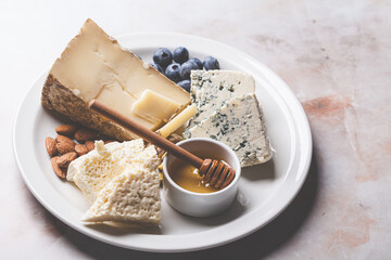 Cheese plate for party with honey, nuts and berries.