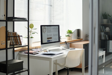 Background image of small office workplace with statistics graphics on PC screen copy space