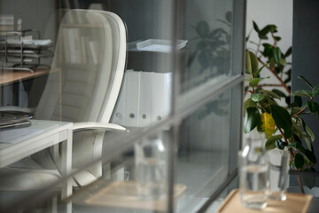 Detail image of modern office interior with glass partitions and distorted leather office chair, copy space