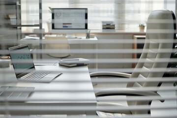 Side view at managers workplace with tall leather chair at desk behind glass partition, no people, copy space