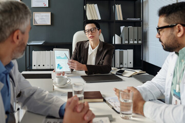 Front view portrait of mature woman as female manager presenting statistics report to employees during meeting in office