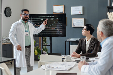 Portrait of mature Middle Eastern man as doctor giving presentation during medical conference and...