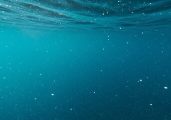 Obraz premium Bubbles rise in a column through deep blue water, illuminated by sunlight filtering from above the surface.