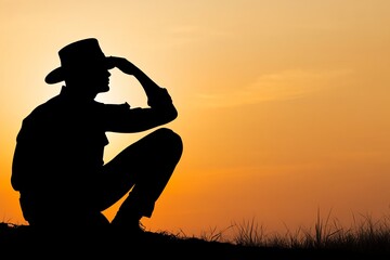 Silhouette of cowboy at sunset looking far away.