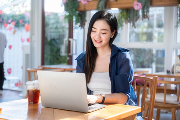 Fototapeta premium Asian freelance people business female talking making using casual working with laptop computer and coffee at home in the living room indoors artificial rose bouquet of red and pink roses rose vase