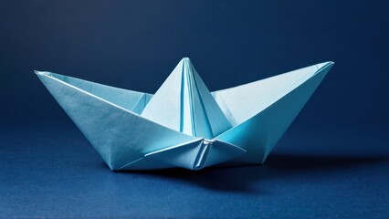 Obraz premium a delicate blue origami boat rests gracefully against a deep blue backdrop