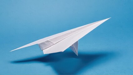  a minimalist paper airplane glides effortlessly against a vibrant blue backdrop
