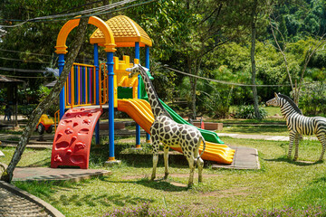 A vibrant playground in a lush jungle setting, featuring a colorful play structure and animal...