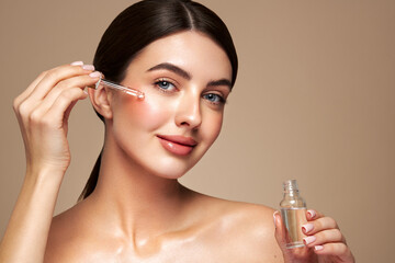 Young beautiful woman applying face serum with pipette. Cosmetic procedures for facial skin care