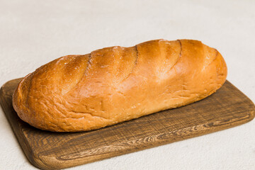 Freshly baked bread on cutting board against white wooden background. perspective view bread with copy space