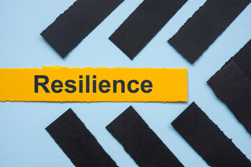 Strips of paper and the word resilience. Mental strength and overcoming challenges.