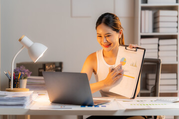Remote Work Presentation: A focused woman smiles, actively presenting financial data on a clipboard during a virtual meeting, symbolizing the modern remote work environment.