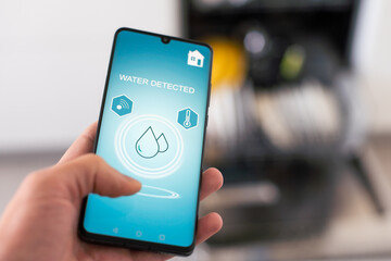 Man turns on the dishwasher by smartphone application.