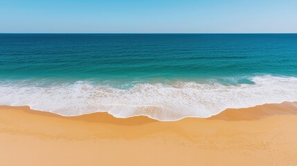 Fototapeta premium A serene beach scene showcasing golden sand meeting a calm blue ocean under a clear sky.