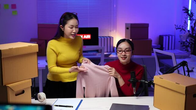 Smiling influencers showing clothes on live stream