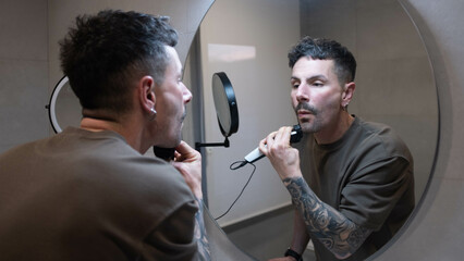 man trimming his beard in front of the mirror