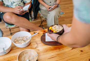 Unrecognizable chef showing vegan breakfast bowl made with mango, banana, raspberries, cereals and muesli to audience taking notes in a cooking master class. Healthy cooking workshop concept.
