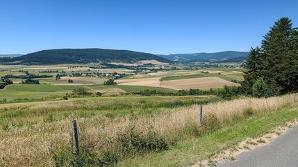 Naklejka premium Serene Rural Landscape Rolling Hills Fields and Blue Sky