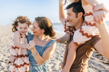 Family of Four at the beach smiling in dresses