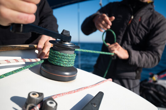 Sailors adjusting sailboat rope on a winch during regatta